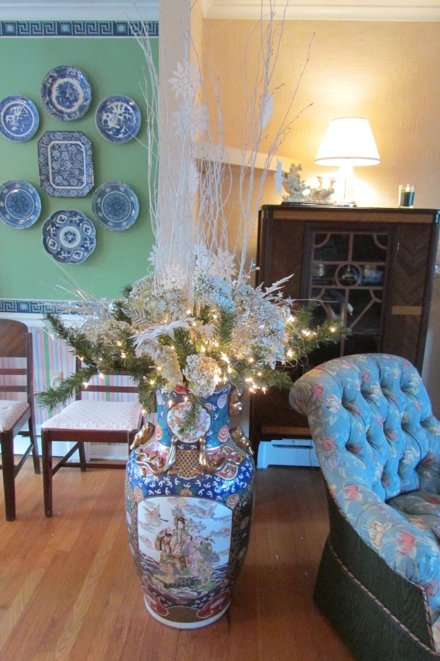 A large Chinese floor vase filled with wintry plant materials.