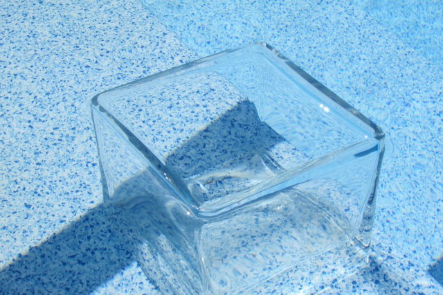 A clear glass vase, on the first step in the pool, used to determine if it evaporation or some other kind of leak in the in-ground pool.