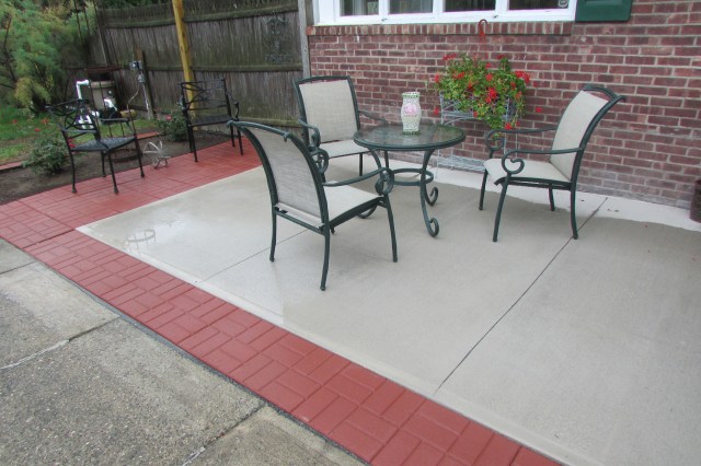 Extending a poured cement patio with sixteen inch square brick-face stepping stone/ patio pavers. 